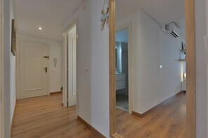 A hallway with wooden flooring, white walls, and a door leading to a bathroom. - Paraiso Mar Apartments in Calpe VICTORIA (Calpe / Calp)