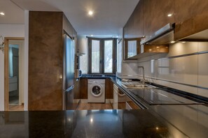 A compact kitchen with a washing machine, a sink, and a window with curtains. - Paraiso Mar Apartments in Calpe VICTORIA (Calpe / Calp)