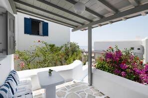 Un bâtiment blanc avec un volet bleu, un sol en pierre et une vue sur la mer.