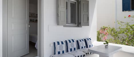 Una habitación con un banco blanco, una mesita y una puerta que da a otra estancia.
