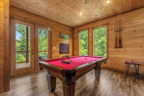 A pool table in a wooden room with large windows and doors. - Hilltop Dreamin': Life's Better Up Here (Sevierville)