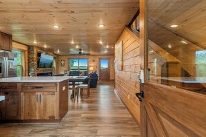 A wooden interior with a kitchen area, dining space, and a view through a window. - Hilltop Dreamin': Life's Better Up Here (Sevierville)