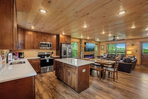 A spacious kitchen with wooden cabinets, a large island, and modern appliances. - Hilltop Dreamin': Life's Better Up Here (Sevierville)
