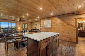 A spacious kitchen with wooden cabinets, a large island, and a dining area with a sofa and table. - Hilltop Dreamin': Life's Better Up Here (Sevierville)