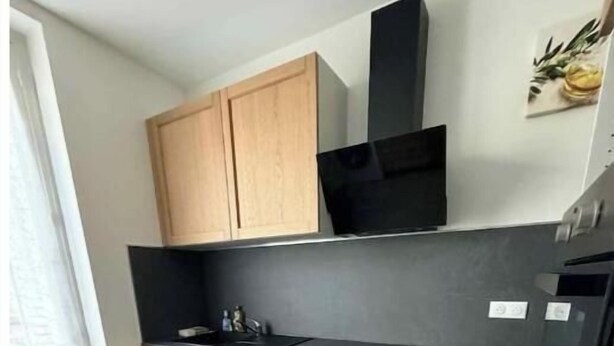 Una cucina con mobili in legno, un piano di lavoro nero, una lavastoviglie e una cappa aspirante nera.