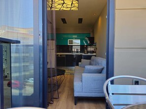 Un intérieur moderne avec un canapé gris, un coin repas et une cuisine aux meubles verts.