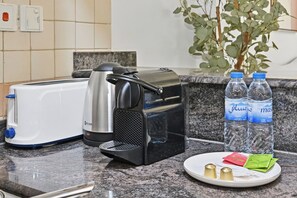 Eine Küchenarbeitsplatte mit einem Toaster, einer Kaffeemaschine, zwei Wasserflaschen und einem Teller mit Gewürzen.