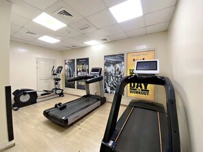 Ein Fitnessstudio mit Laufbändern, Crosstrainern und einem Ergometer.