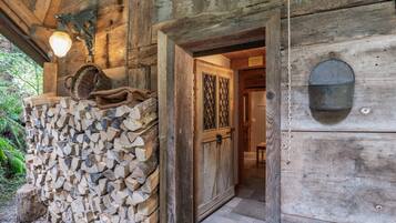 Ein rustikales Holzgebäude mit Holzstapel, einer Metalllaterne und einer Tür mit Metallriegel.