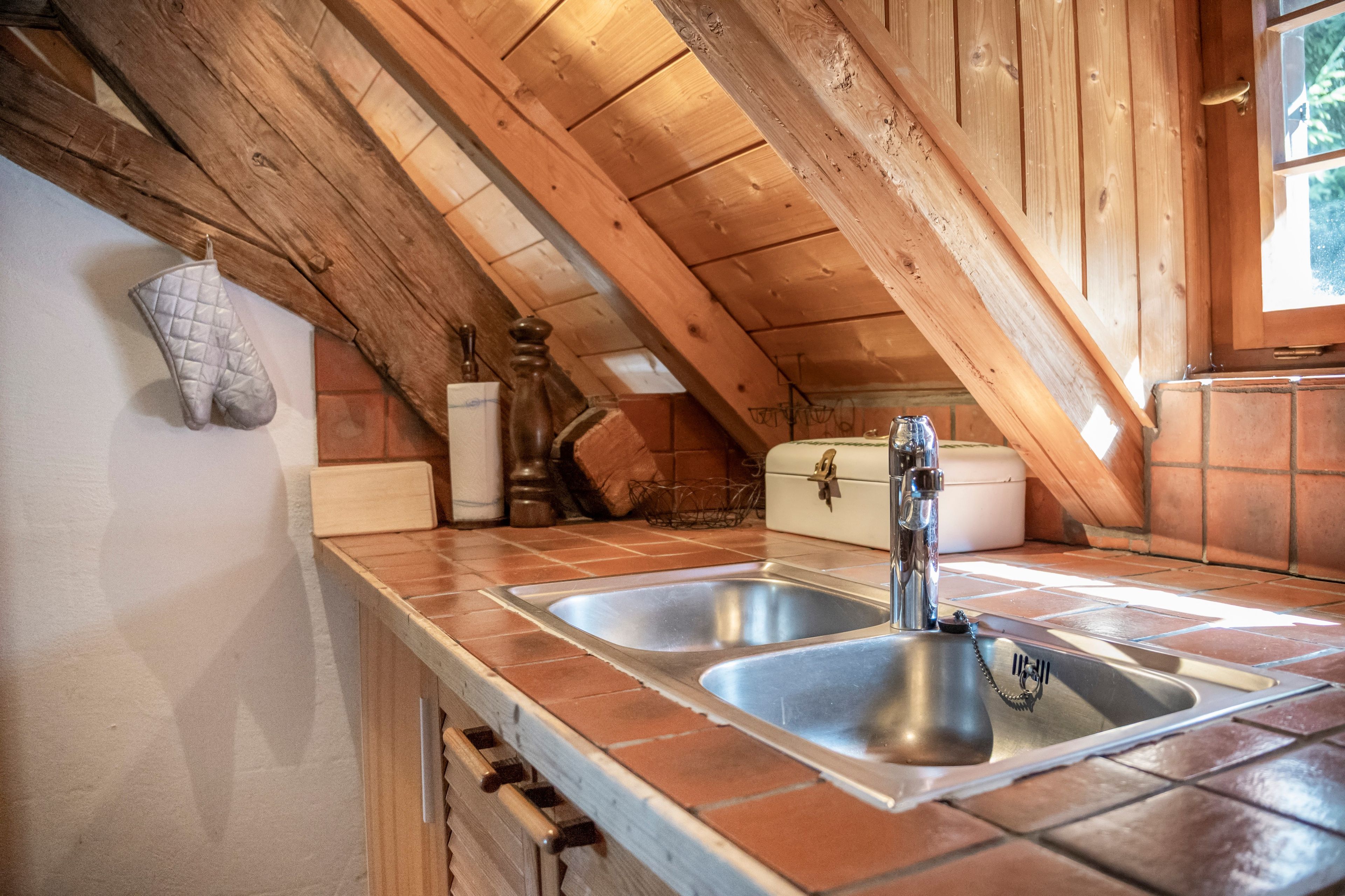 Une cuisine avec un plafond en bois, deux éviers en acier inoxydable et une fenêtre.