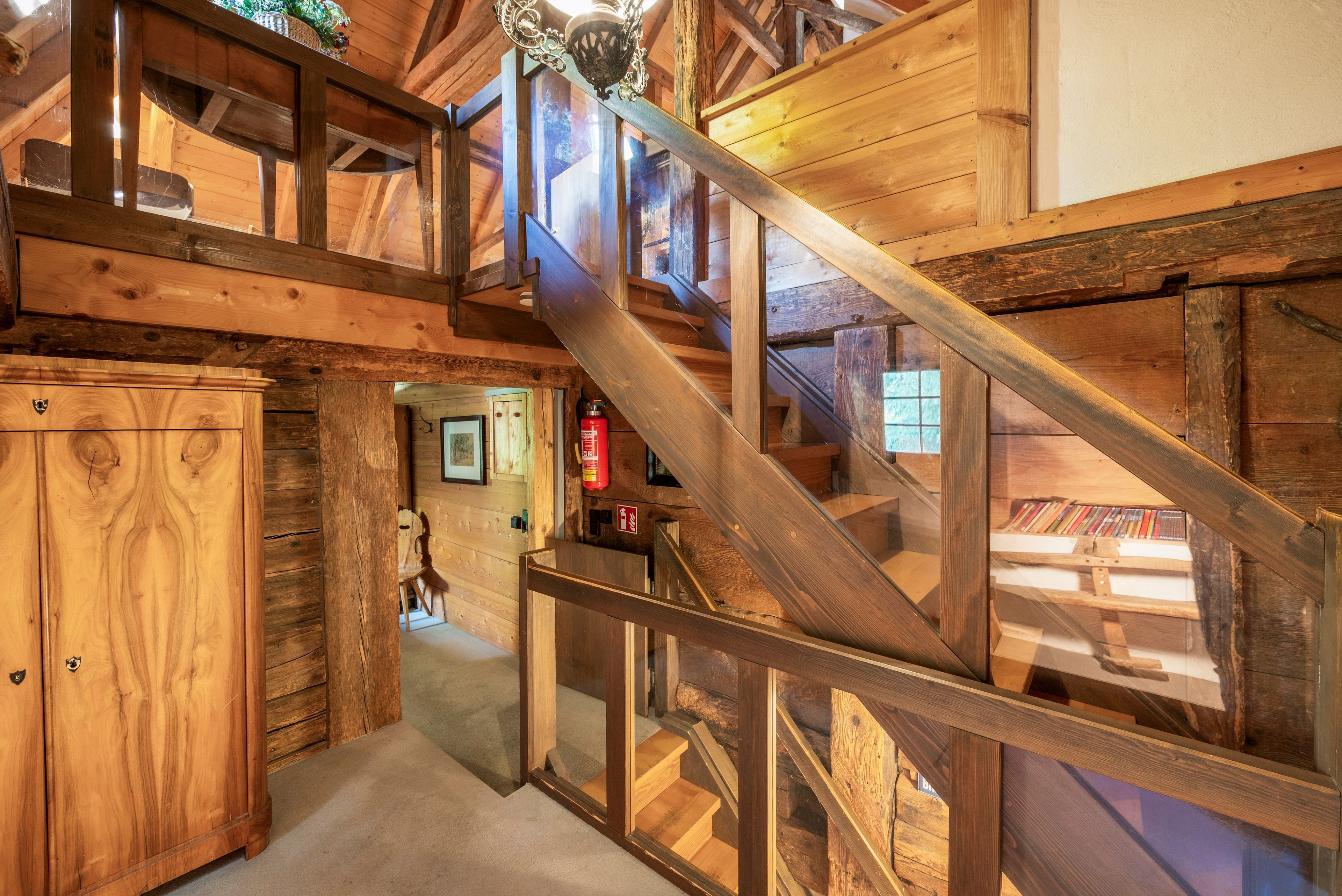 Un escalier en bois avec une rampe en verre menant à un espace situé au deuxième étage.