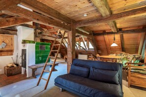 Un intérieur rustique avec un plafond en bois, un canapé, une échelle et un appareil électroménager vert.