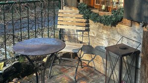 A rustic outdoor seating area with a table, chairs, and a lantern.