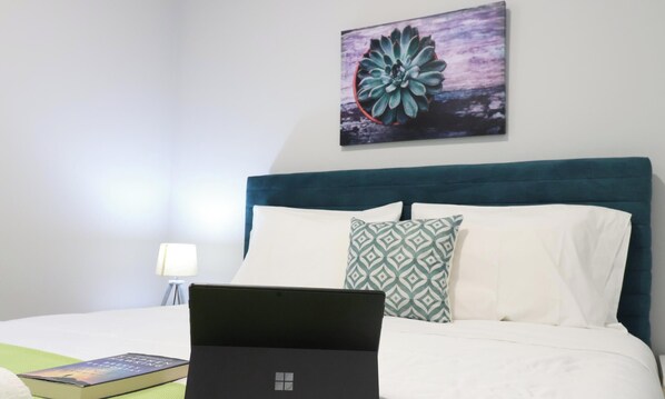 A neatly made bed with a laptop, a book, and a patterned pillow. - MyStay - Casa Pedrosa (Viana do Castelo)