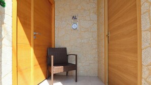Eine Holztür mit einer Steinwand, einer Bank und einem Schild mit einer Zimmernummer.