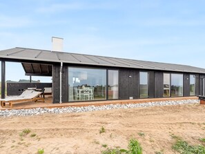 A modern house with a covered patio, large windows, and a sandy landscape. - "Pia" - 350m from the sea by Interhome (Knebel)
