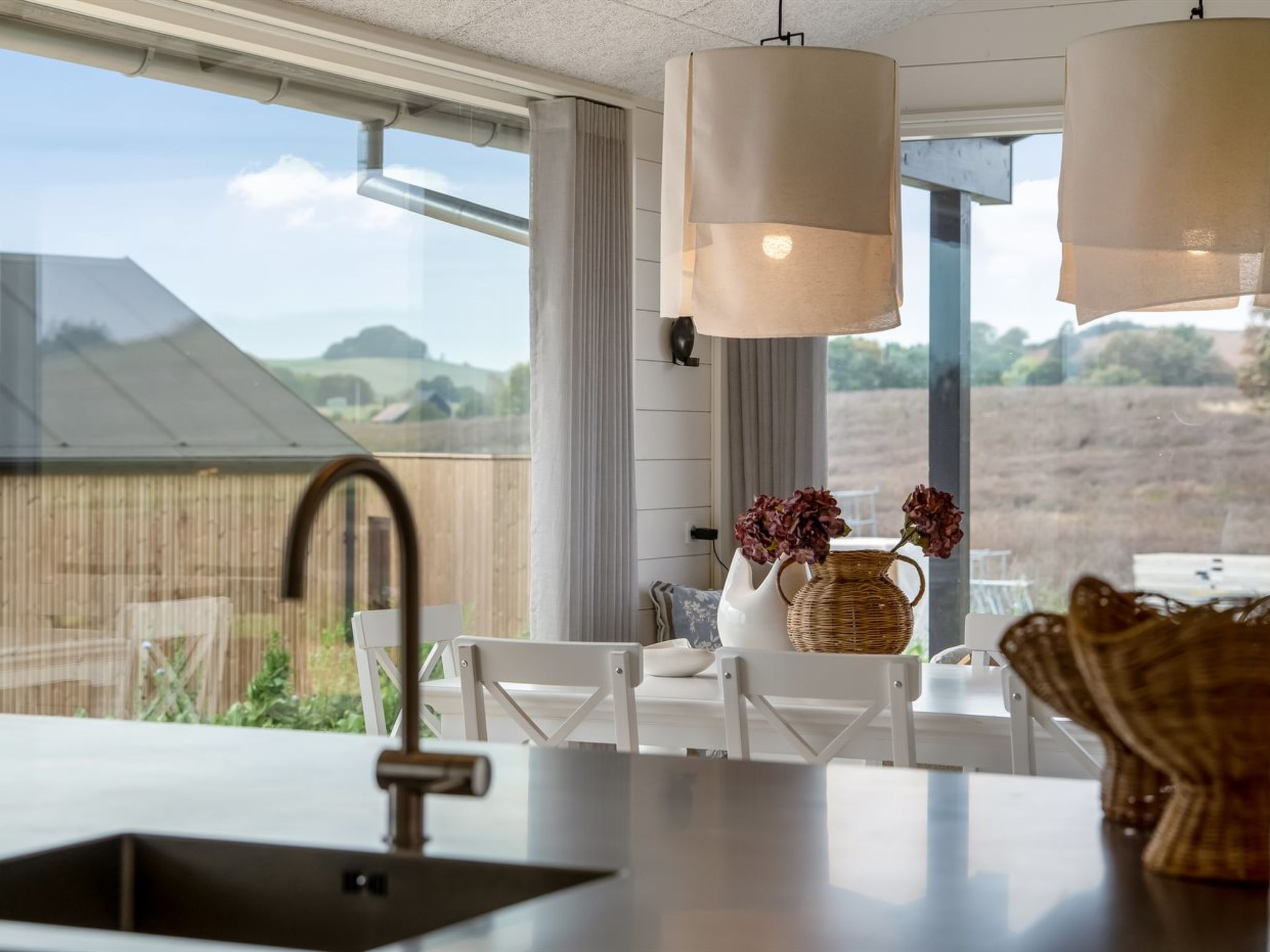 A modern kitchen with a large window, a sink, and hanging pendant lights.