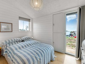 A bedroom with a bed, a window with a view, and a door leading to an outdoor area. - "Pia" - 350m from the sea by Interhome (Knebel)
