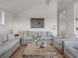 Un salon moderne avec une table basse en bois, des canapés gris et un tableau accroché au mur.