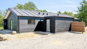 Un bâtiment moderne, de plain-pied, doté d’un toit en pente et d’une façade en bois.