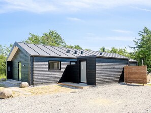 Ein modernes, eingeschossiges Gebäude mit Satteldach und Holzfassade.