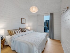 A bedroom with a bed, bedside lamps, a framed picture, and a view through a door. - "Pia" - 350m from the sea by Interhome (Knebel)