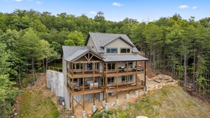 A multi-story cabin with a balcony, surrounded by forest. - Thunderhead Mountain Lodge- Amazing Views, Amazing Private Pool & Game Room (Sevierville)