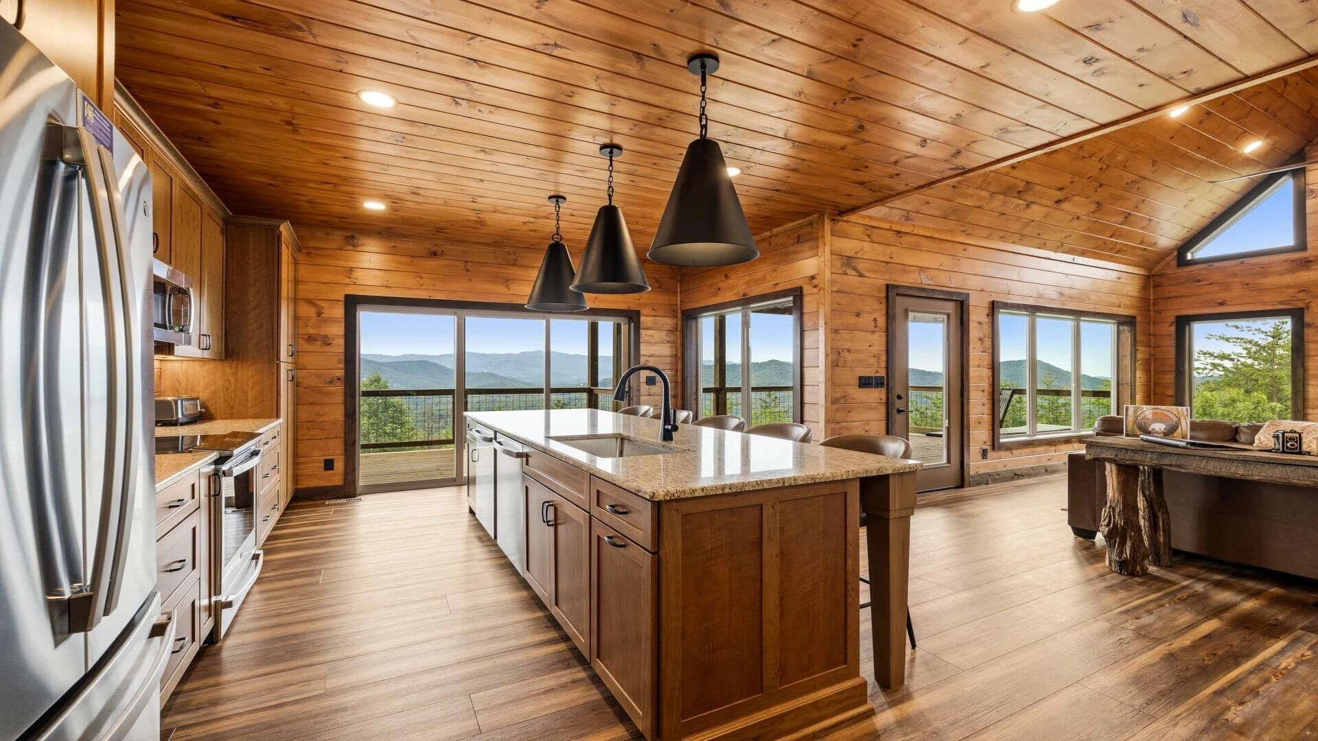 A spacious kitchen with wooden floors, a large island, and a view of mountains through the windows.