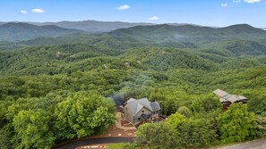 A house surrounded by dense forest with a clear view of distant mountains. - Thunderhead Mountain Lodge- Amazing Views, Amazing Private Pool & Game Room (Sevierville)