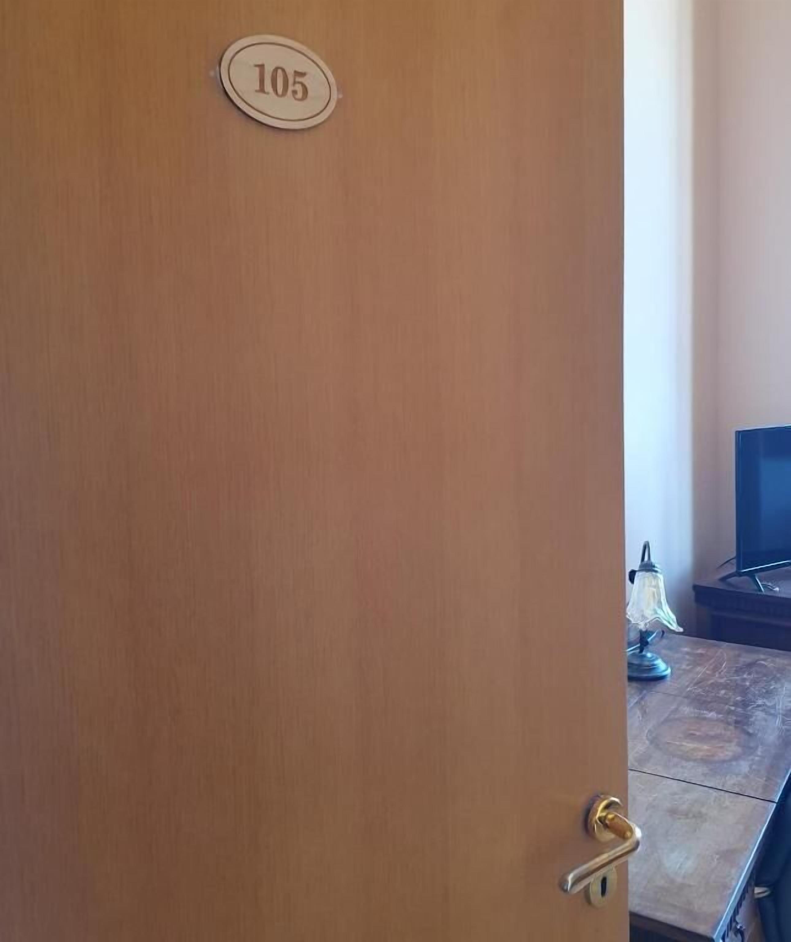 A wooden door with a number plate labeled '105' and a brass door handle.