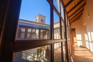 A corridor with a view of a building's exterior through a window, including a bell tower.