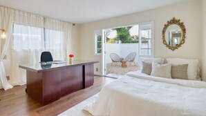 Een slaapkamer met een bed, een bureau, een stoel en een grote spiegel.