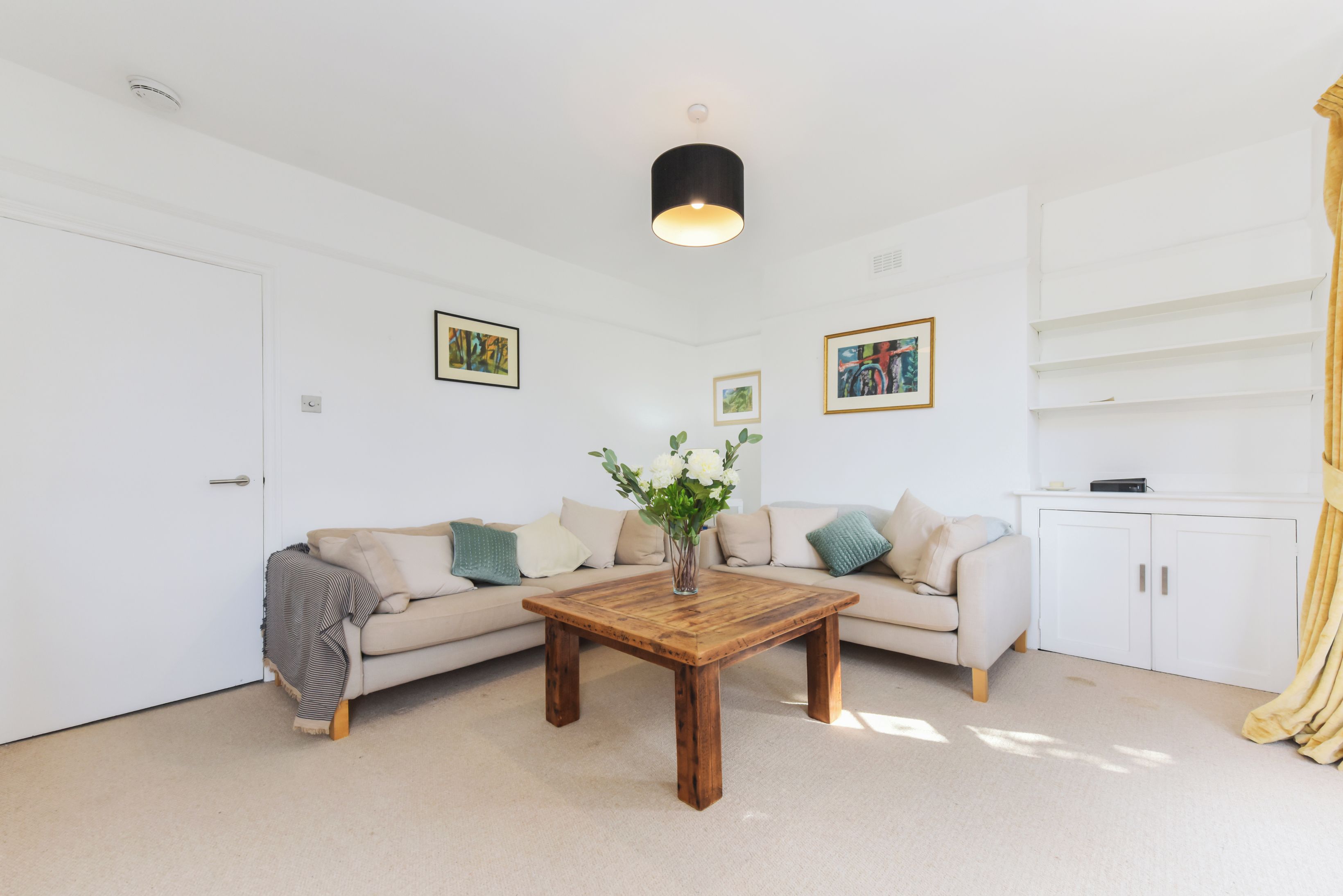 Un salon moderne avec un canapé beige, une table basse en bois et un meuble blanc.