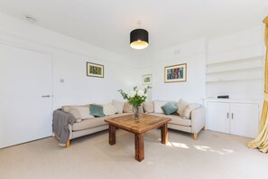 A modern living room with a beige sofa, a wooden coffee table, and a white cabinet. - Spacious 3BDR On The Southbank With Balcony (Greater London)