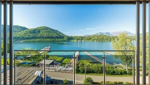 Vista da un balcone su un lago con montagne sullo sfondo.