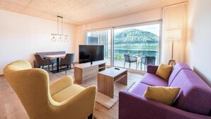 Un soggiorno moderno con un divano, poltrone, televisione e un balcone con vista.