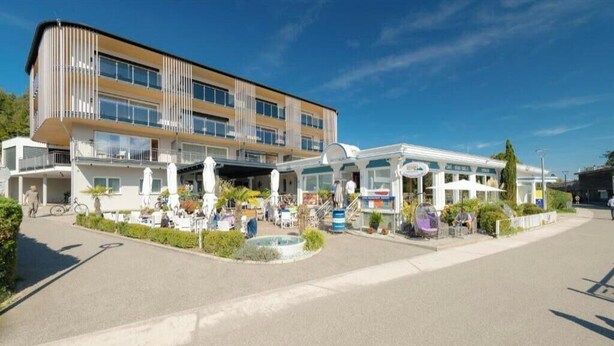 Un hotel moderno con un edificio a più piani, area salotto esterna e ingresso coperto.