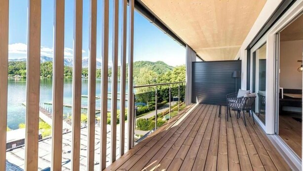 Eine Holzterrasse mit Blick auf einen See und Berge.