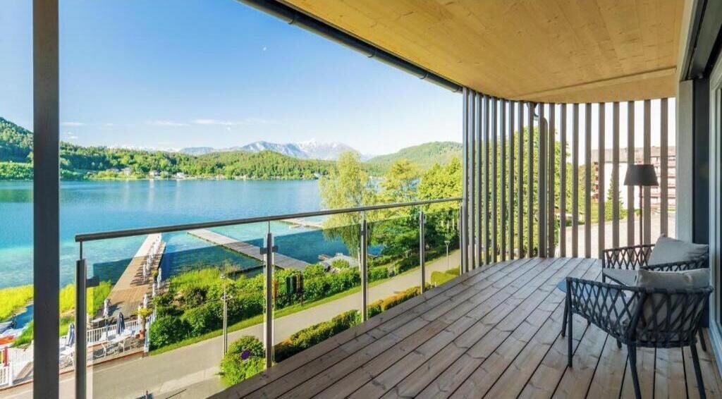 Ein Balkon mit Blick auf einen See und Berge, ein Stuhl und eine Lampe.