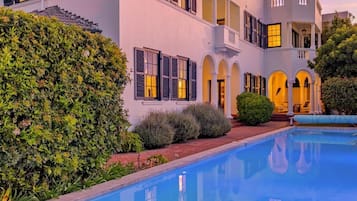Un edificio con piscina, ventanas arqueadas y una siega bien cuidada.