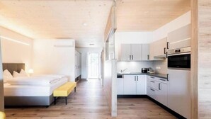 Une chambre d’hôtel moderne équipée d’un lit, d’une table de chevet et offrant une vue sur la cuisine.