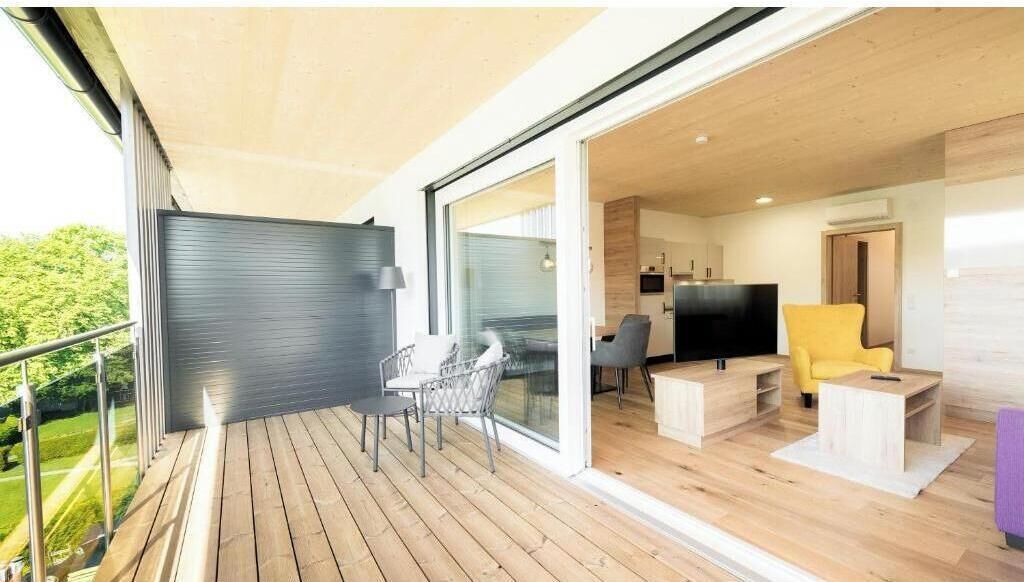 A modern interior with a balcony, a dining area, and a living room with a TV.
