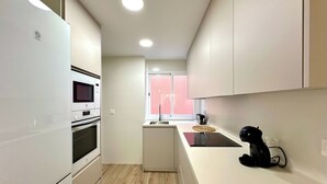 A modern kitchen with white cabinetry, a built-in oven, a microwave, and a coffee machine. - TWIN BEACH Apartments, just 10 steps from the beach (Torrenueva)
