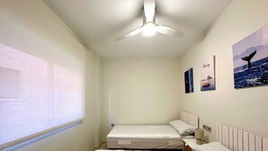 A hotel room with two beds, a ceiling fan, a window with a view, and wall art. - TWIN BEACH Apartments, just 10 steps from the beach (Torrenueva)