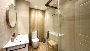A modern bathroom with a glass-enclosed shower, a toilet, and a sink with a mirror. - TWIN BEACH Apartments, just 10 steps from the beach (Torrenueva)
