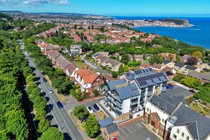 An aerial view of a residential area with houses, a road, and a body of water in the background. - The Penthouse, Scarborough (Scarborough)