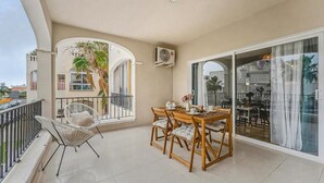 Un balcone con un tavolo da pranzo, sedie e una pianta in vaso.
