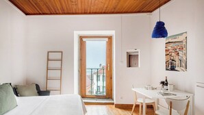 Un dormitorio con cama, escritorio, silla, escalera y balcón con vistas.