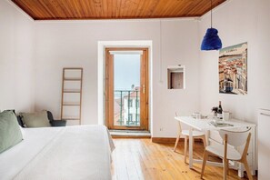 A bedroom with a bed, a desk, a chair, a ladder, and a balcony with a view. - Bright Studio With Open Views Alfama (Lisbon)