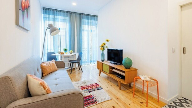A modern living room with a sofa, TV, and a small table with a vase. - Urban Studio Bonfim (Porto)
